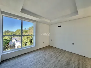 Uma sala interna com grande janela que oferece vista para a vegetação externa.