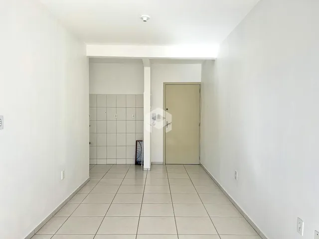 Corredor interno de uma residência com paredes brancas e piso de cerâmica.