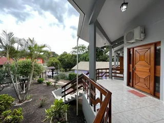 Foto da varanda coberta de uma residência em Lajeado, mostrando degraus de madeira e um jardim ao fundo.