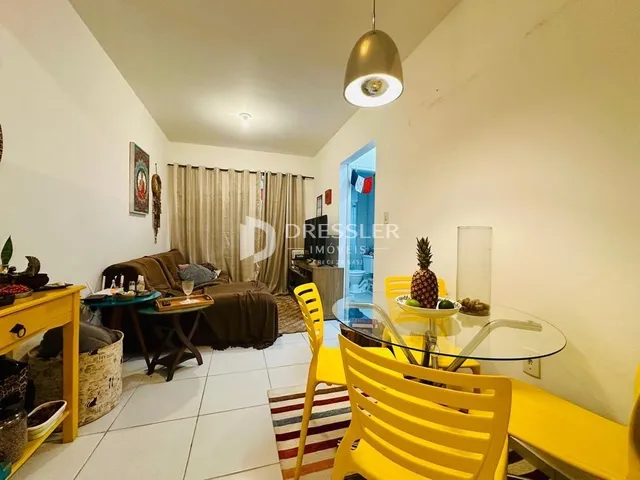 Uma sala de estar clara com piso de cerâmica e móveis amarelos.