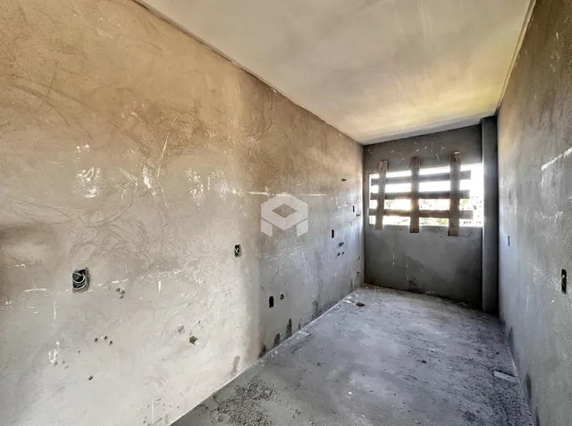 A foto mostra um corredor interno com paredes de concreto aparente.