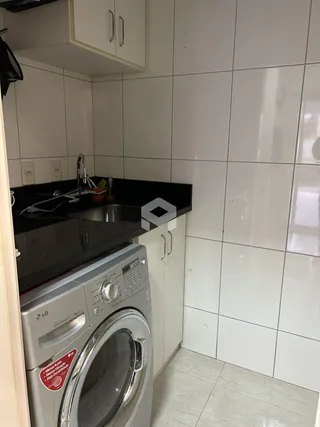 Cozinha com armários brancos e bancada preta.
