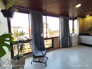 Sala com grandes janelas e teto de madeira na residência.