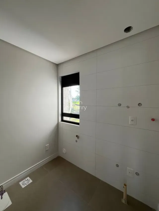 Hall de corredor com paredes brancas e uma janela escura.