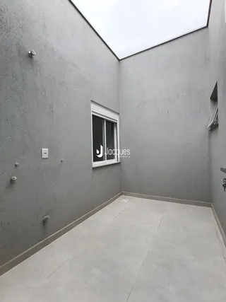 Vista de um corredor interno com paredes cinzas e piso de cerâmica.