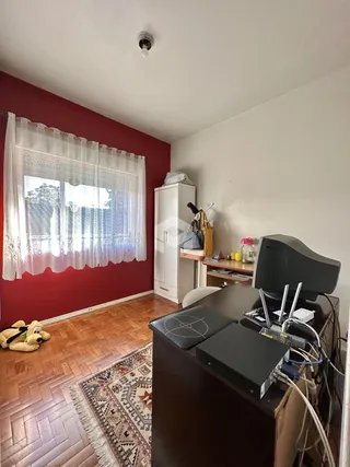 Quarto com parede vermelha e piso de madeira em Lajeado, Brasil.