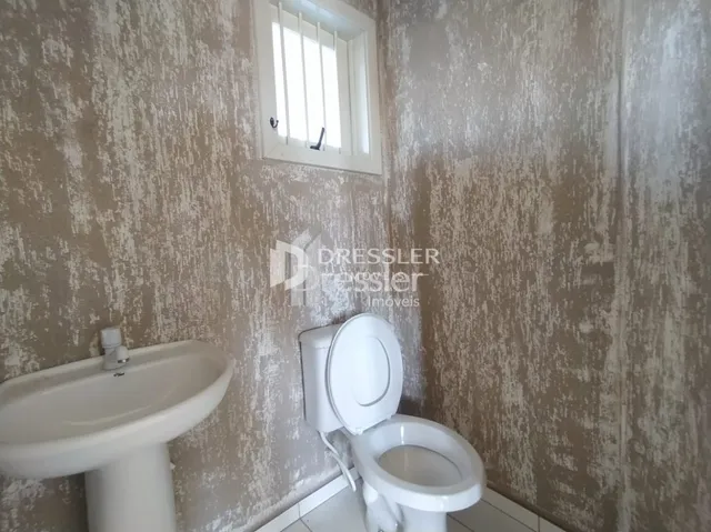 Foto de um banheiro interno com vaso sanitário branco e parede texturizada.