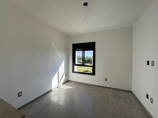 Ambiente interno com paredes brancas e piso de concreto em um imóvel.
