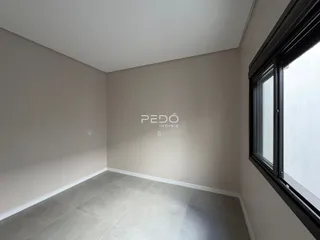 Interior de uma sala com paredes neutras e piso claro.