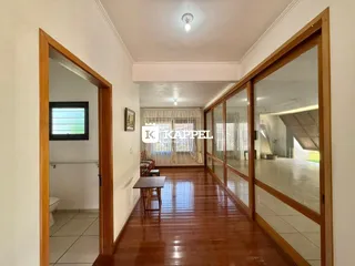 Corredor com piso de madeira polida e portas de vidro que levam a outras áreas da casa.