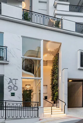 Fachada moderna de um edifício residencial com detalhes em vidro e vegetação.