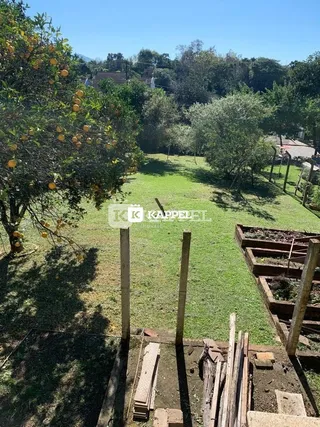 Vista externa mostrando um gramado com árvores e estruturas de madeira.