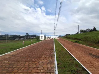 Vista externa de uma estrada pavimentada com grama nas laterais em uma área rural.