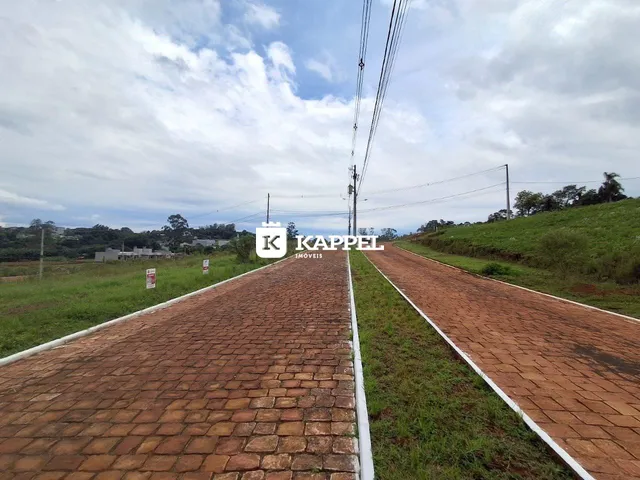 Vista externa de uma estrada pavimentada com grama nas laterais em uma área rural.