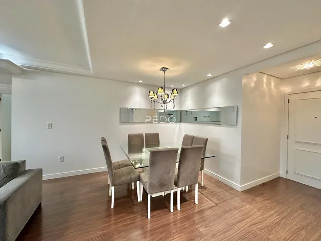 Uma sala de jantar com mesa de vidro e cadeiras em um imóvel em Lajeado.