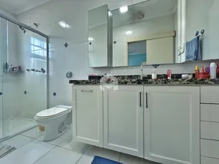 Foto de um banheiro com revestimento cerâmico e armários brancos.