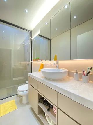 Foto de um banheiro moderno com box de vidro e bancada clara.