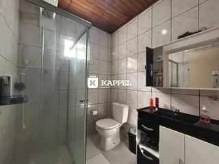 Foto de um banheiro com revestimento de cerâmica e box de vidro.