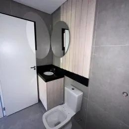 Foto de um banheiro com vaso sanitário e bancada escura.