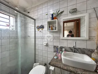 Foto de um banheiro com revestimento cerâmico e box de vidro.