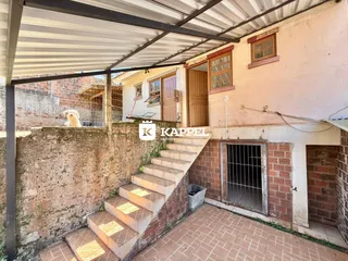 Vista externa mostrando uma escadaria de tijolos que leva a uma área coberta da residência.