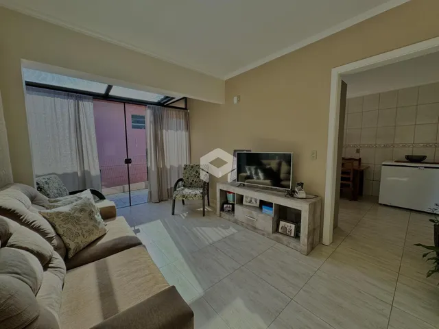 Sala de estar com sofá e porta de vidro abrindo para o exterior.