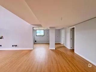 Vista interna de um ambiente amplo com piso de madeira clara.