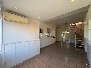Sala de estar com piso de madeira e detalhes em painel branco.