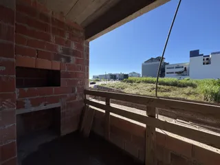 Parede de tijolos vermelhos com uma abertura para o exterior e uma estrutura de madeira.