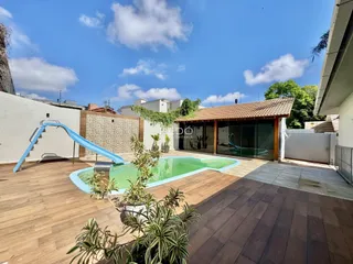 Foto da área externa com piscina e deck de madeira.
