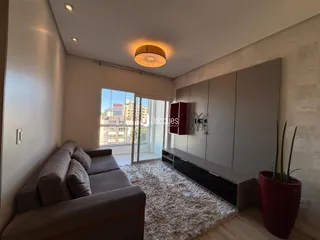 Sala de estar com sofá e painel de parede em um apartamento no Brasil.