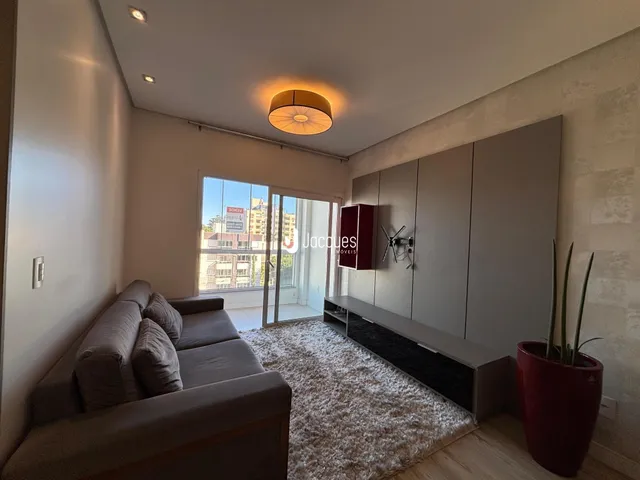 Sala de estar com sofá e painel de parede em um apartamento no Brasil.