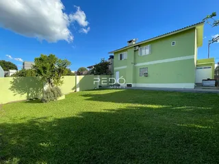 Fachada de uma casa verde com gramado verde no primeiro plano.