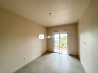Hall de entrada com piso claro e porta de vidro que dá acesso a uma área externa.