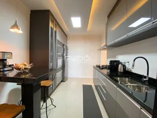 Uma cozinha moderna com armários escuros e piso claro.