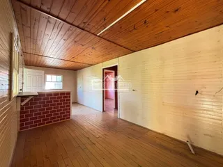 Ambiente interno com piso de madeira e teto inclinado na residência.