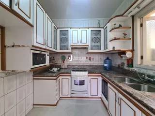 Foto de uma cozinha com armários brancos e bancadas de granito.