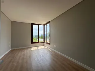 Sala de estar com piso de madeira e vista para a paisagem externa.
