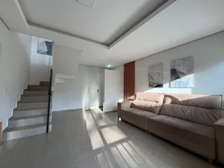 Sala de estar ampla com sofá e escadaria em um ambiente claro.
