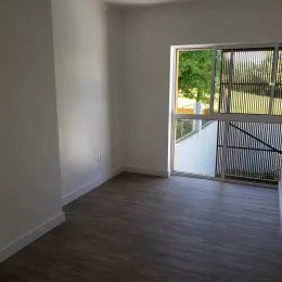 Foto de um corredor interno com paredes brancas e piso escuro.