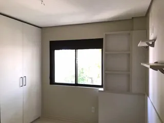 Vista interna de um quarto com armários e janela em uma residência.