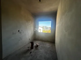 Vista interna de um corredor com paredes brancas e piso de concreto.