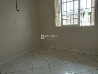Foto do interior de uma sala com piso de cerâmica clara e uma grande janela.