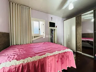Quarto com cama rosa e janela de madeira.