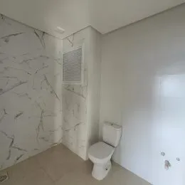 Foto de um banheiro com revestimento de mármore branco nas paredes.