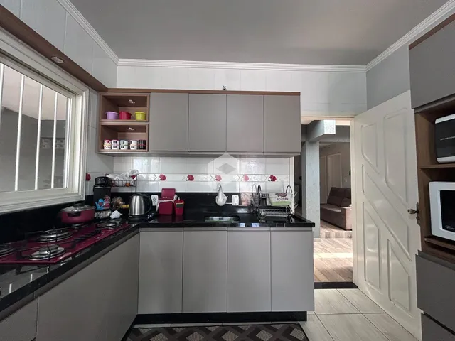 Uma cozinha moderna com armários cinzas e bancadas escuras.