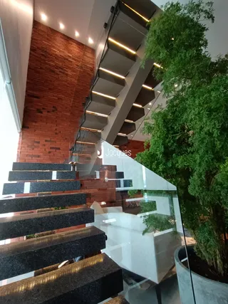 Uma escadaria moderna com parede de tijolos vermelhos é visível no interior da propriedade.