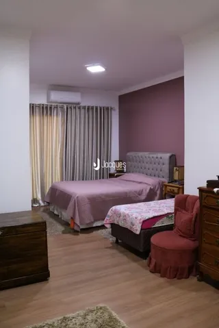 Quarto com cama e piso de madeira em um imóvel.