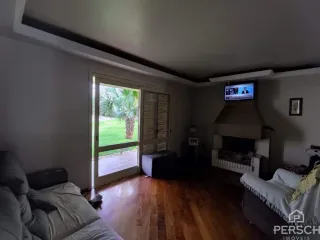 Sala de estar com piso de madeira e vista para o jardim externo.