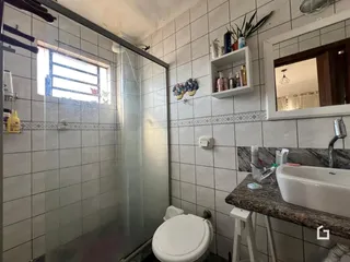 Foto interna de um banheiro com revestimento cerâmico e box de vidro.